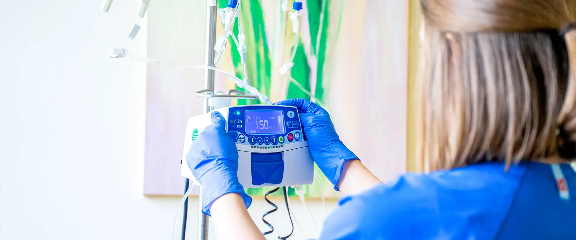 Pflegekraft stellt eine Infusionspumpe im Therapieraum der Praxis ein